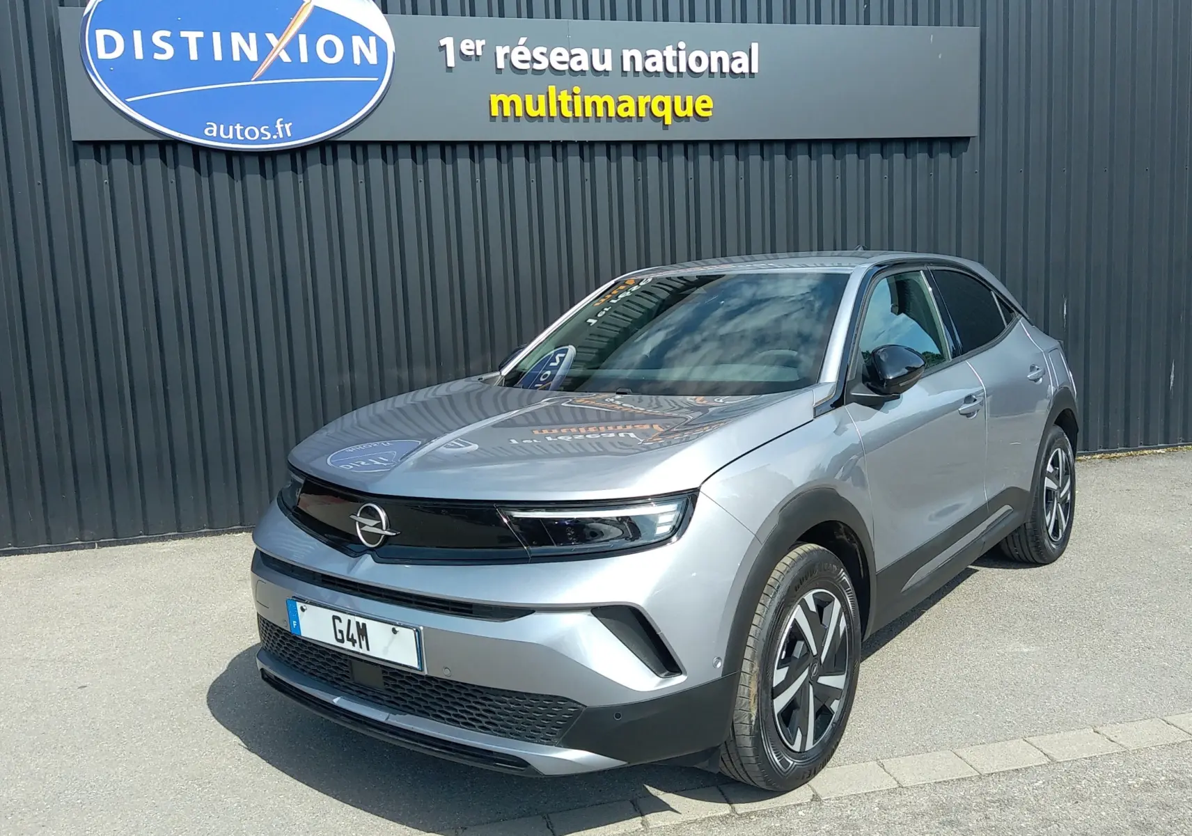Opel Mokka Electric gris en 3/4 avant droit, SUV compact électrique avec calandre noire et jantes stylisées.