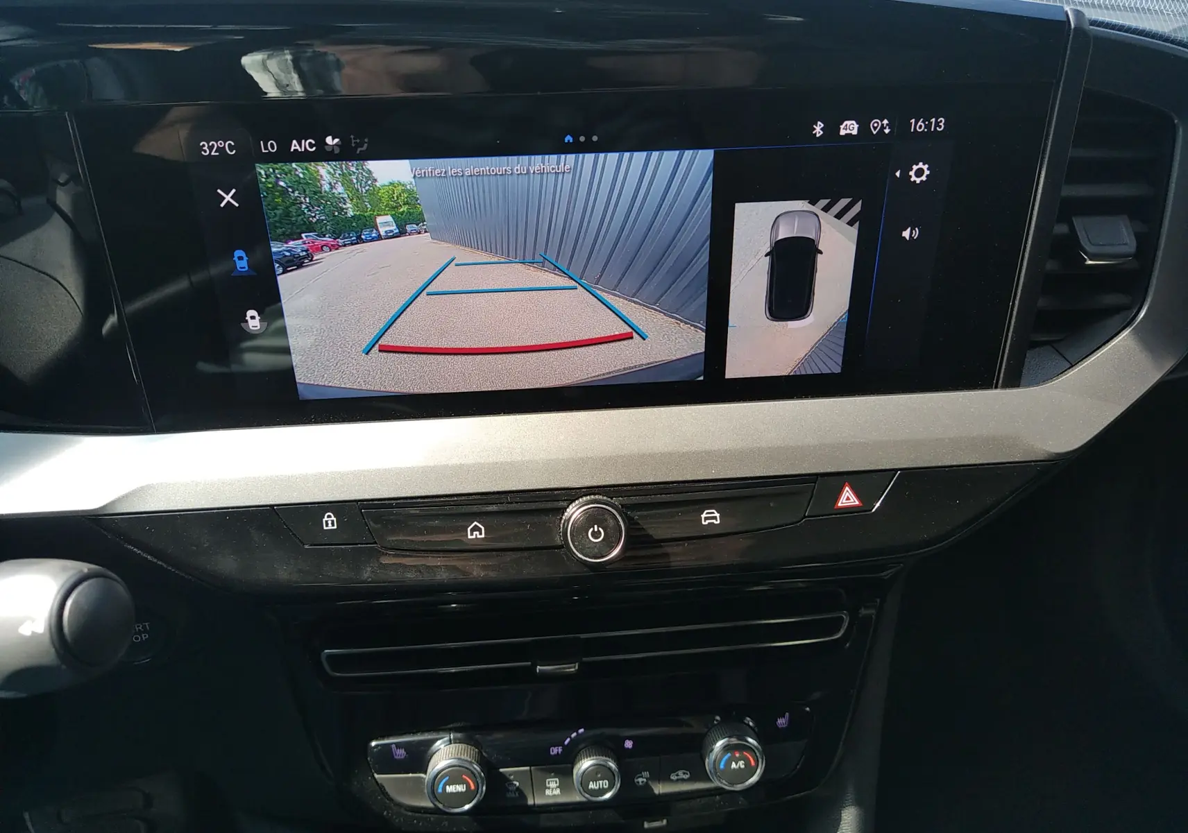 Vue intérieure du tableau de bord de l’Opel Mokka électrique gris, avec écran affichant la caméra de recul et l’aide au stationnement.