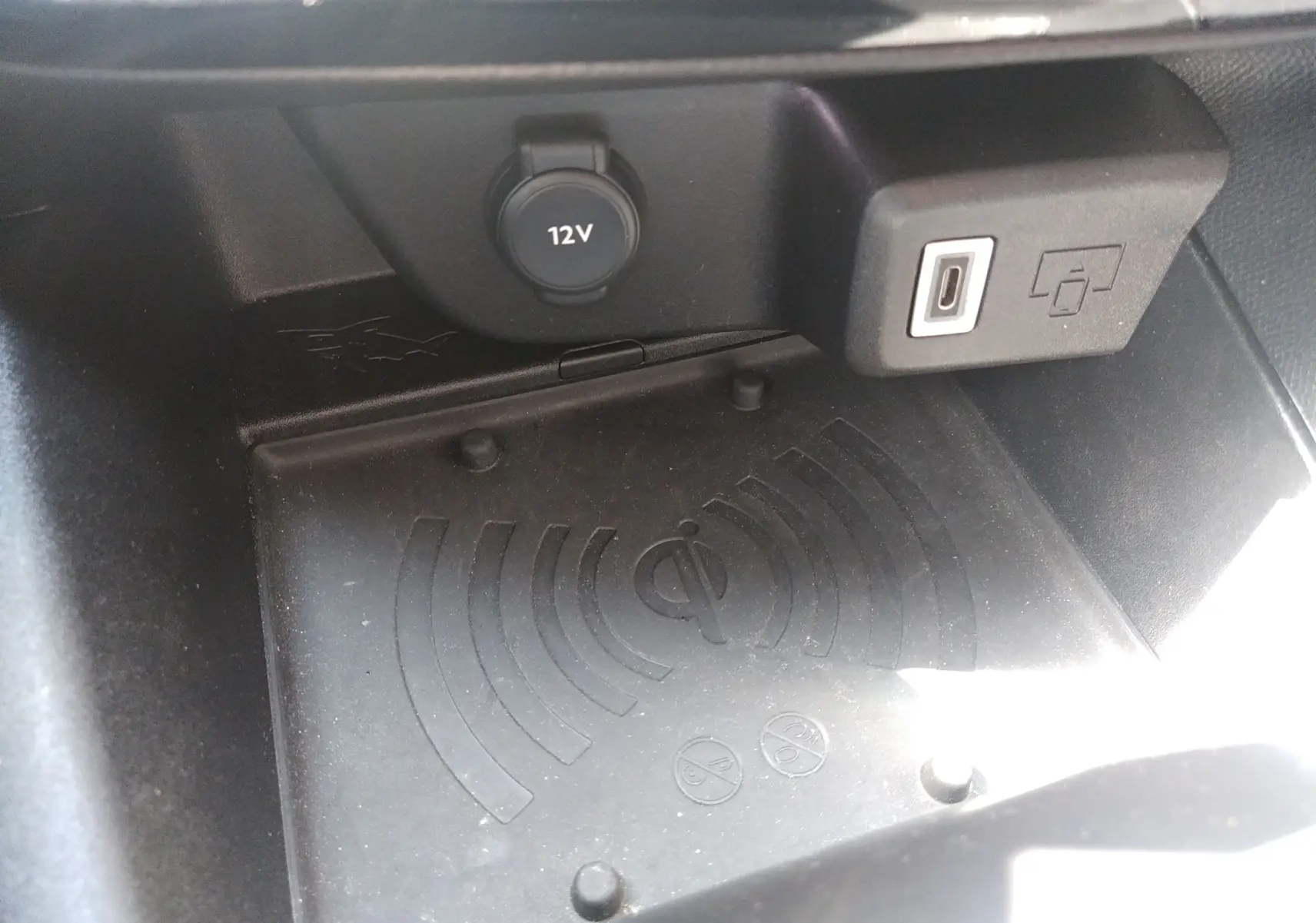 Gros plan sur la zone de recharge sans fil et prise USB dans l'habitacle noir de l'Opel Mokka Electric gris.