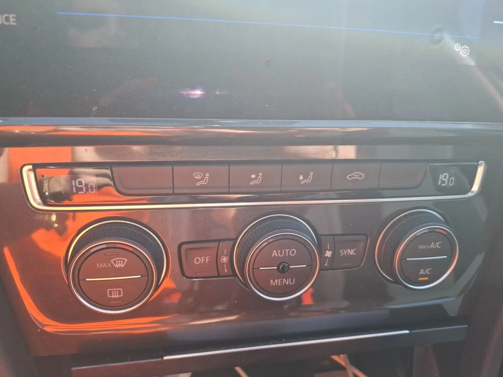 Gros plan sur la console centrale de la Volkswagen Golf blanche, montrant la climatisation automatique bi-zone à 19°C.