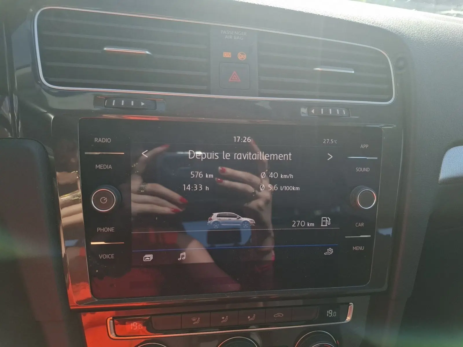 Écran tactile central de la Volkswagen Golf blanc, affichant les données de consommation et autonomie, vue de face intérieure.