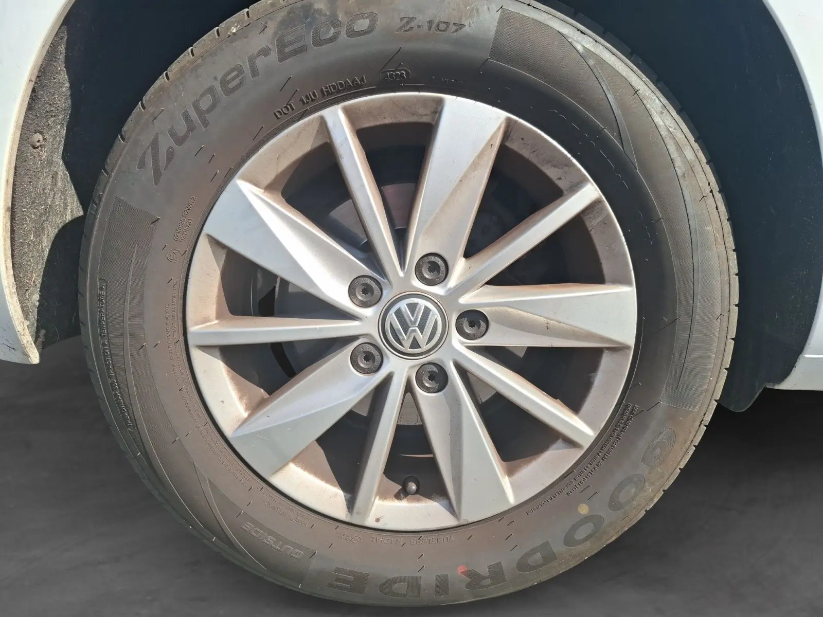 Gros plan sur la jante alliage argentée d'une Volkswagen Golf blanche, mettant en valeur le logo VW central.