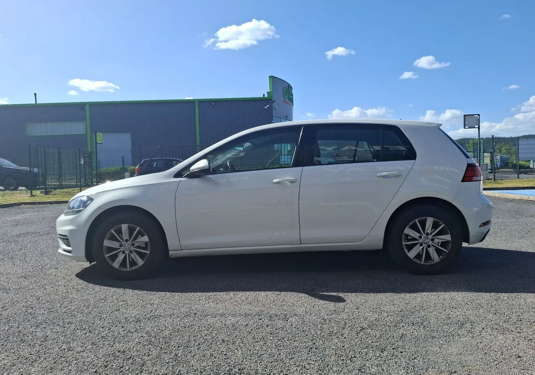 Volkswagen Golf blanc vue de profil côté gauche, avec jantes alliage et vitres teintées, stationnée en extérieur.