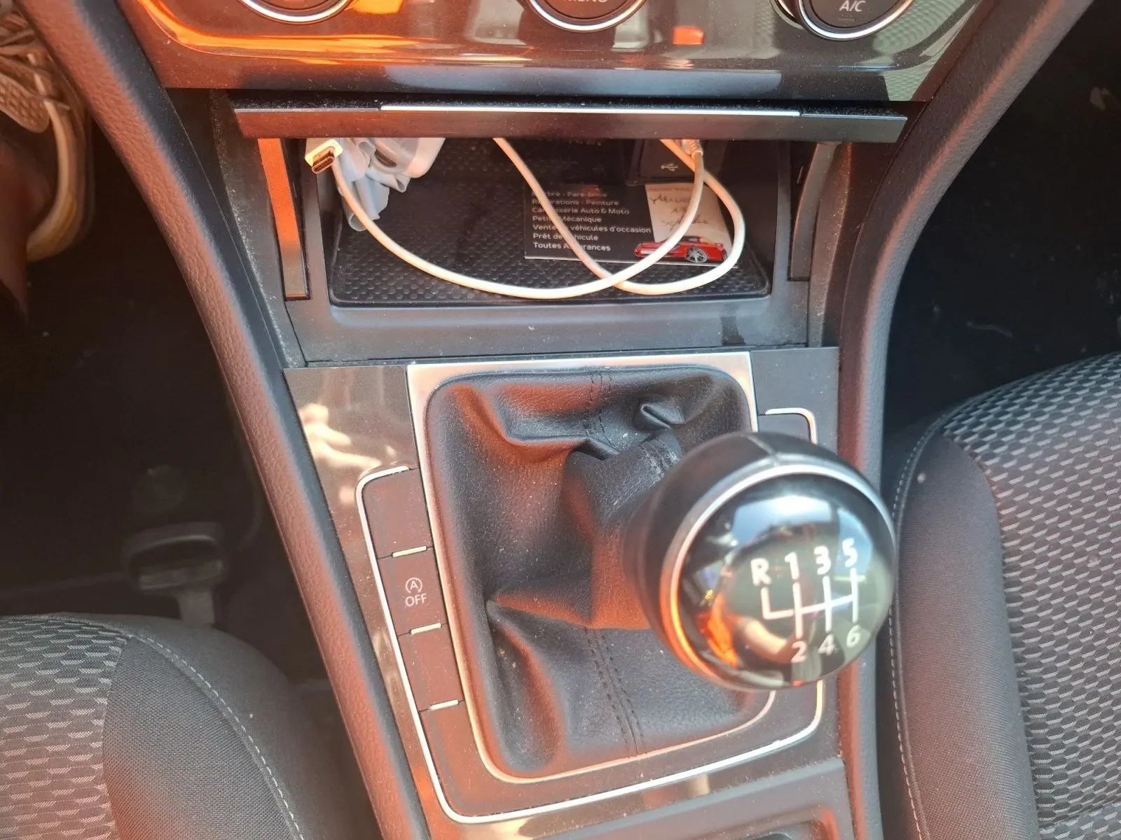 Gros plan sur le levier de vitesses manuel 6 rapports de la Volkswagen Golf blanche, avec console centrale et siège tissu visible.