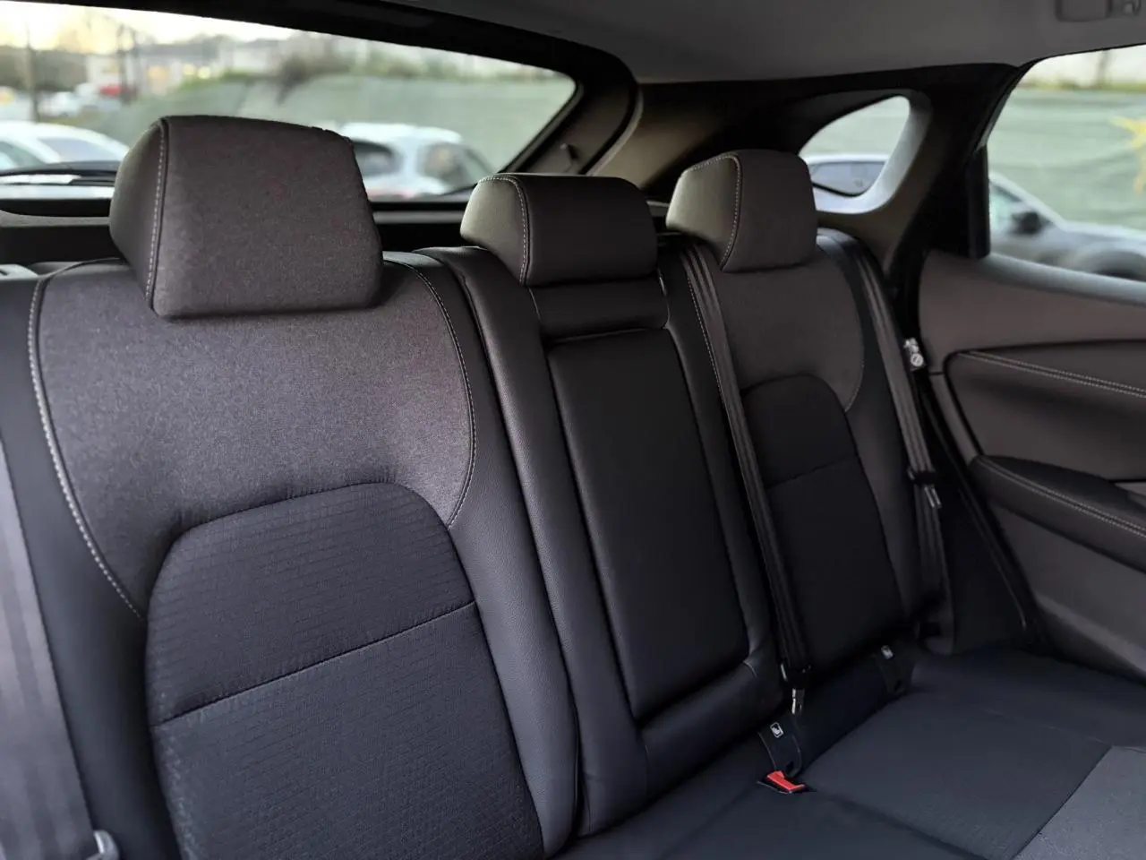 Vue latérale des sièges arrière noirs du Nissan Qashqai 2025, montrant les appuie-têtes et ceintures de sécurité.