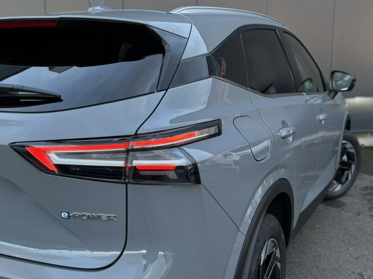 Vue 3/4 arrière droite du Nissan Qashqai 2025 gris Ceramic avec feux arrière LED et badge e-POWER visible.
