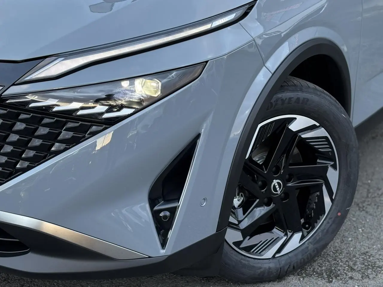 Gros plan sur l'avant droit du Nissan Qashqai gris Ceramic, mettant en valeur le phare LED et la jante alliage noire et argent.