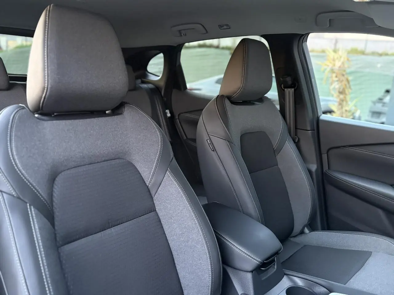 Vue intérieure sur les sièges avant gris et noirs du Nissan Qashqai III e-Power, avec accoudoir central et porte côté droit.