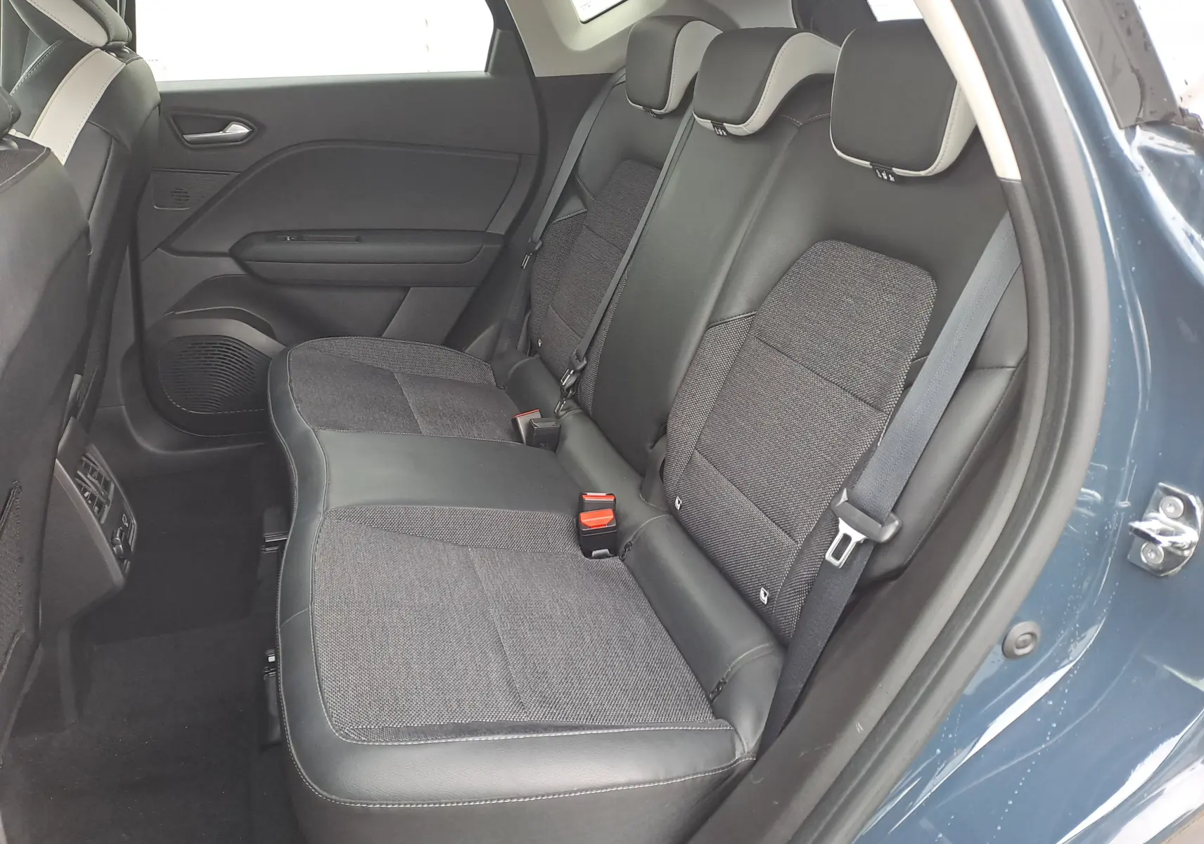 Vue intérieure côté droit des sièges arrière en tissu et cuir noir du Renault Captur bleu marine 2022, porte ouverte.