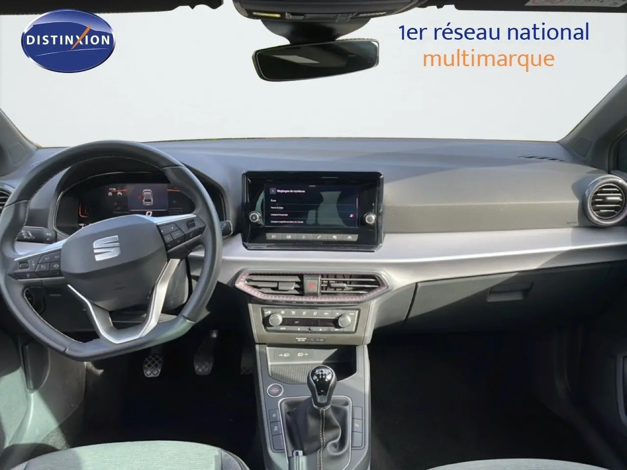 Vue intérieure frontale du tableau de bord de la SEAT Ibiza bleu Fjord 2025 avec volant multifonction et boîte manuelle.