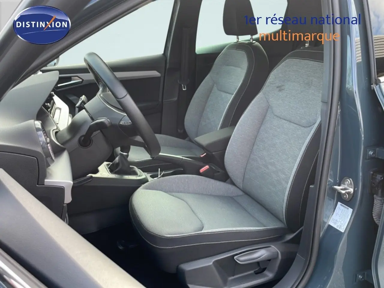 Intérieur côté conducteur d'une SEAT Ibiza bleu fjord 2025, montrant sièges tissu gris et volant multifonction.