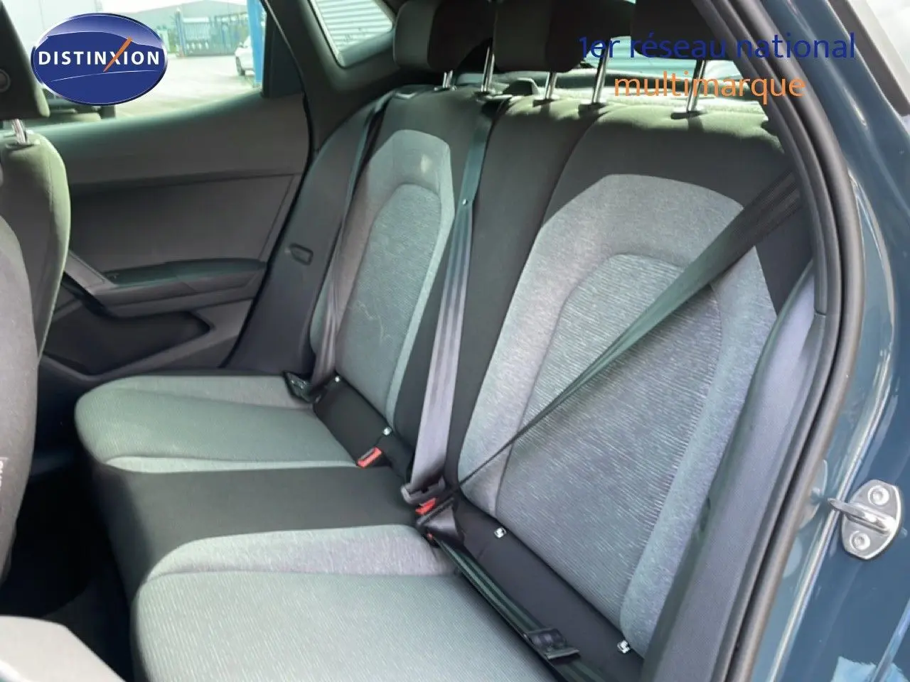 Vue côté droit sur l'intérieur arrière d'une SEAT Ibiza 2025 bleu fjord avec sièges tissu bicolores gris et noir.