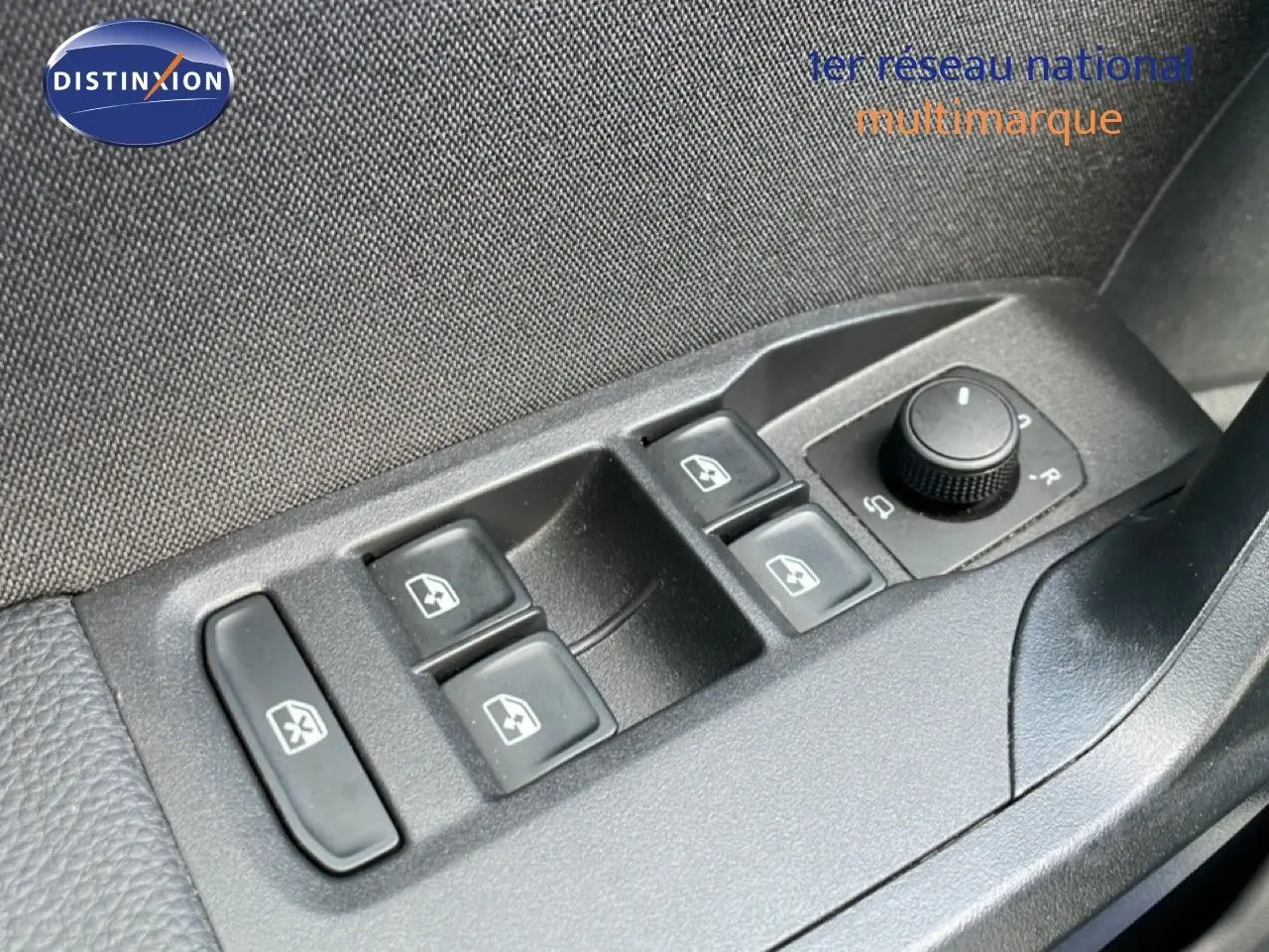 Gros plan sur les commandes des vitres électriques et réglage des rétroviseurs côté conducteur d'une SEAT Ibiza bleu Fjord.