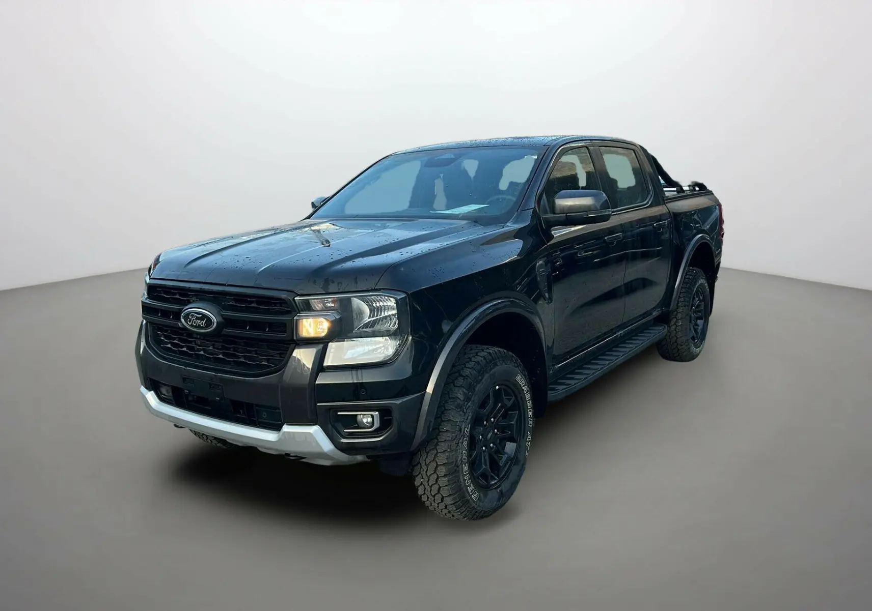 Ford Ranger noir agate en 3/4 avant droit, avec arceaux noirs et marchepieds visibles sous la double cabine.