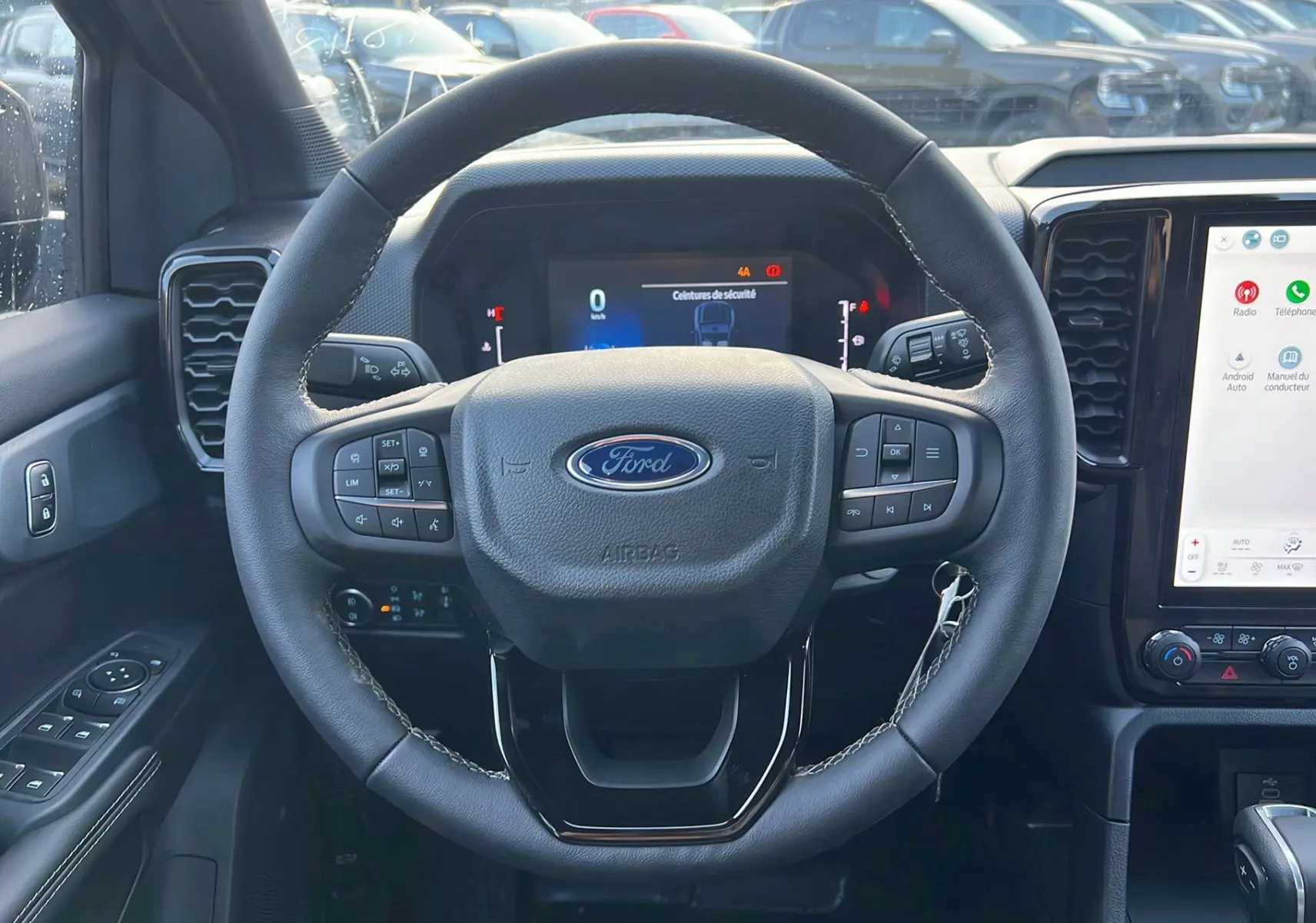 Vue intérieure centrée sur le volant cuir multifonctions du Ford Ranger 2025 avec écran tactile et commandes au volant.