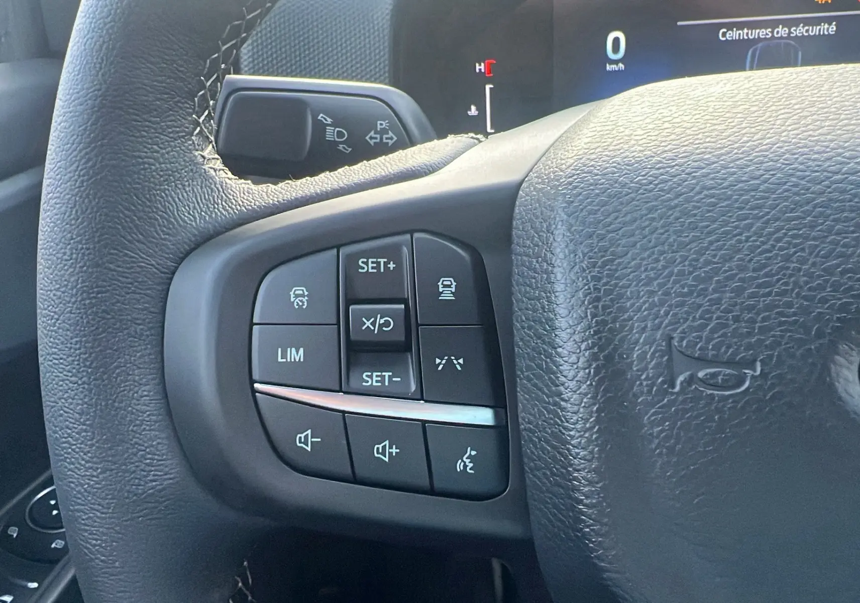 Gros plan sur les commandes multifonctions à gauche du volant cuir du Ford Ranger noir agate 2025.