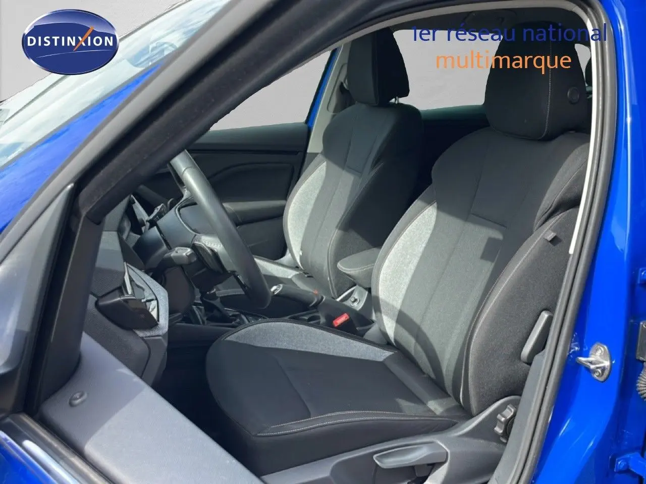 Vue intérieure côté conducteur d'une Skoda Scala bleu racing metal, sièges tissu gris et noir avec volant multifonction.