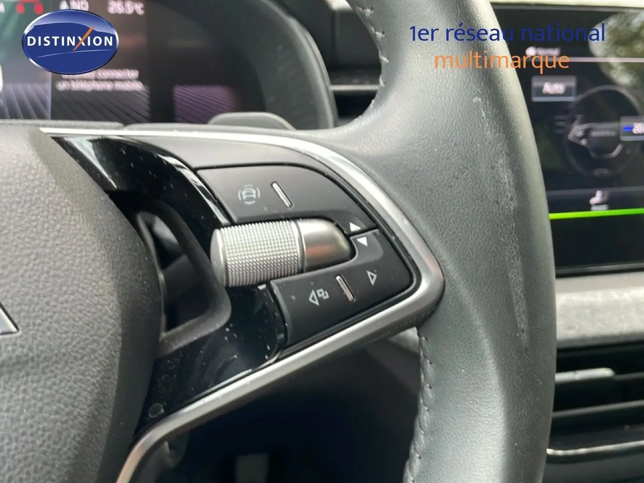 Gros plan sur la partie gauche du volant cuir de la Skoda Scala 2025 avec commandes multifonctions et tableau de bord flou en arrière-plan.