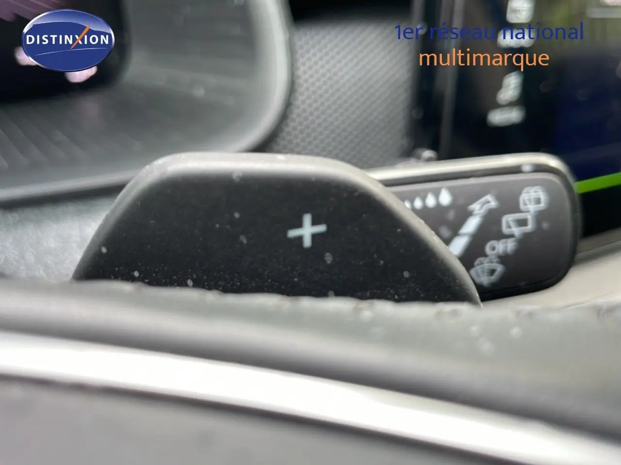 Gros plan sur la palette de changement de vitesse "+" côté droit du volant dans l'habitacle d'une Skoda Scala bleu Racing Metal.