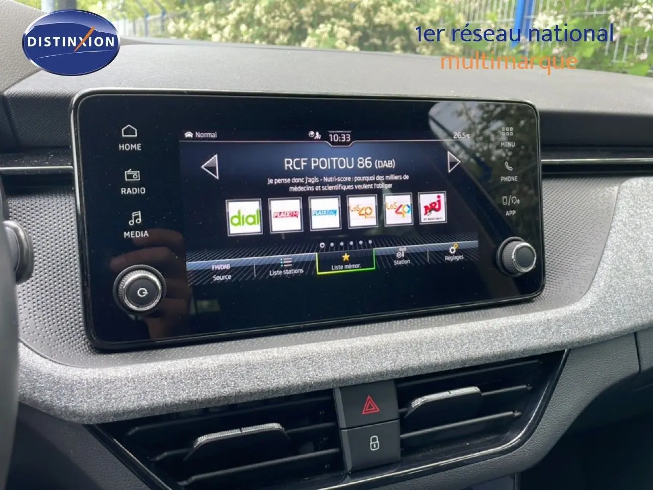 Écran tactile central de la Skoda Scala 2025, affichant les stations radio, avec tableau de bord gris clair texturé.