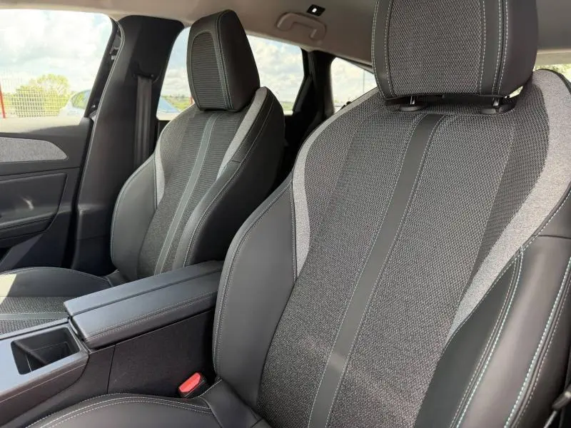 Vue intérieure rapprochée des sièges avant en tissu et cuir du Peugeot 308 SW 1.2 Hybrid 145ch Allure noir Perla Nera.