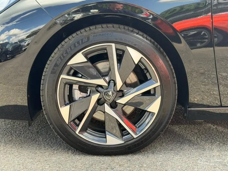 Gros plan sur la roue avant gauche d’une Peugeot 308 SW 1.2 Hybrid 145ch Allure noir Perla Nera avec jante alliage bicolore.