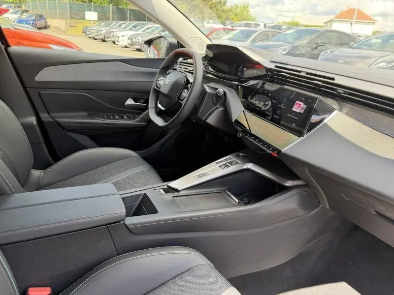 Intérieur de la Peugeot 308 SW 1.2 Hybrid 145ch Allure 2025, vue côté conducteur, tableau de bord moderne noir et gris.