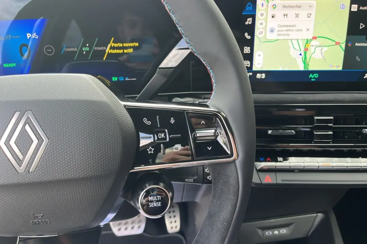 Vue rapprochée du volant cuir multifonctions de la Renault Clio 6 E-Tech 160 Esprit Alpine avec commandes et écran tactile visible.