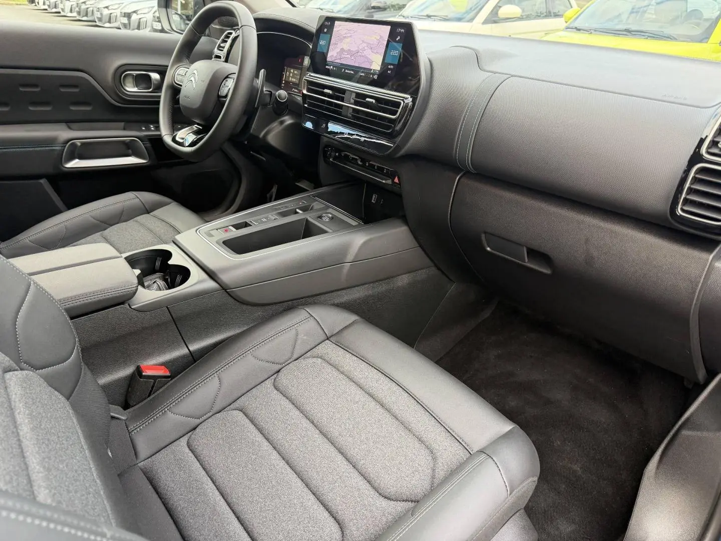 Intérieur avant du Citroën C5 Aircross 2025, vue côté passager, sièges tissu noir et tableau de bord moderne.