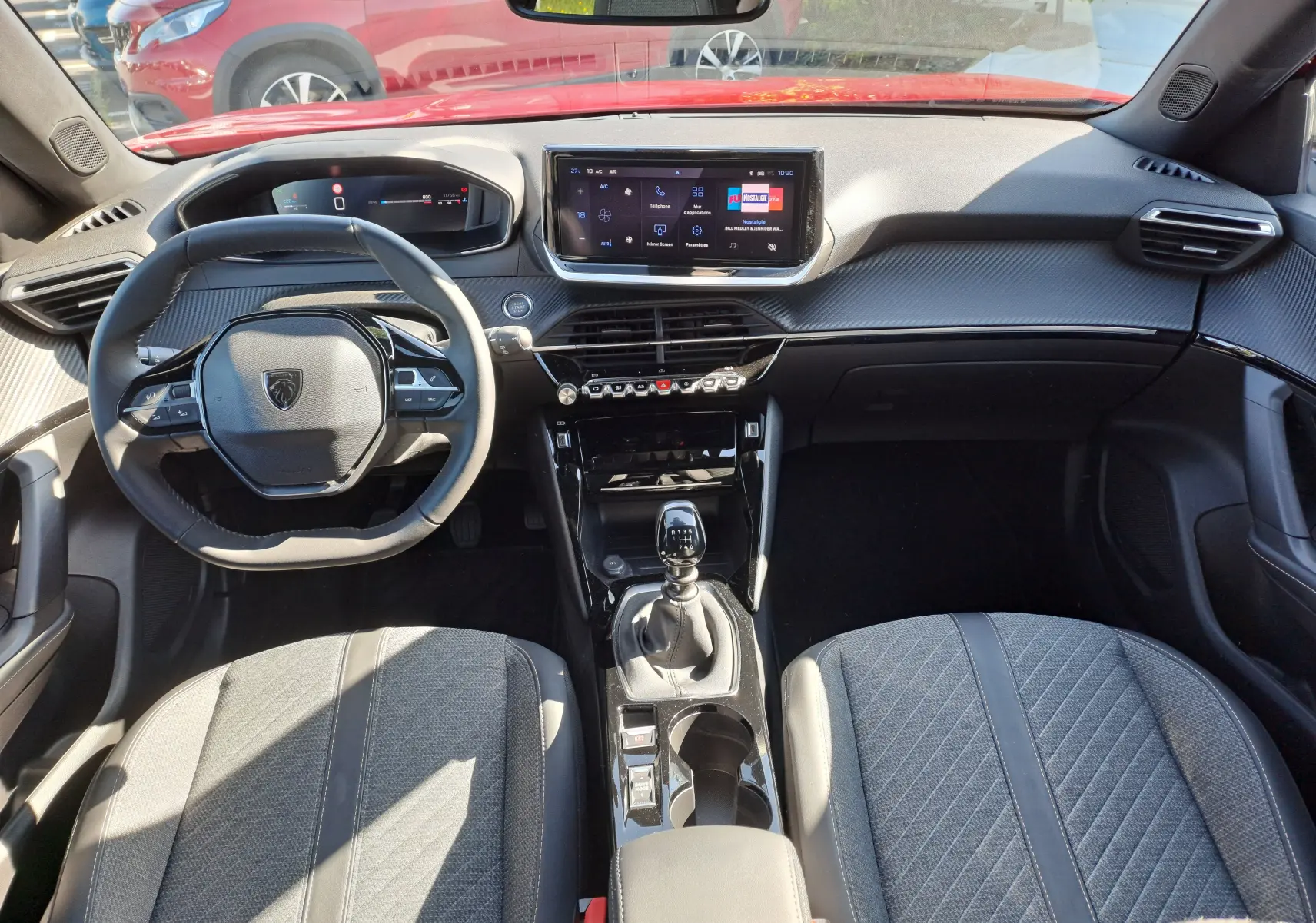 Vue intérieure avant du Peugeot 2008 1.2 PureTech 100 Allure 2023 avec volant compact, écran tactile et levier de vitesse manuel.