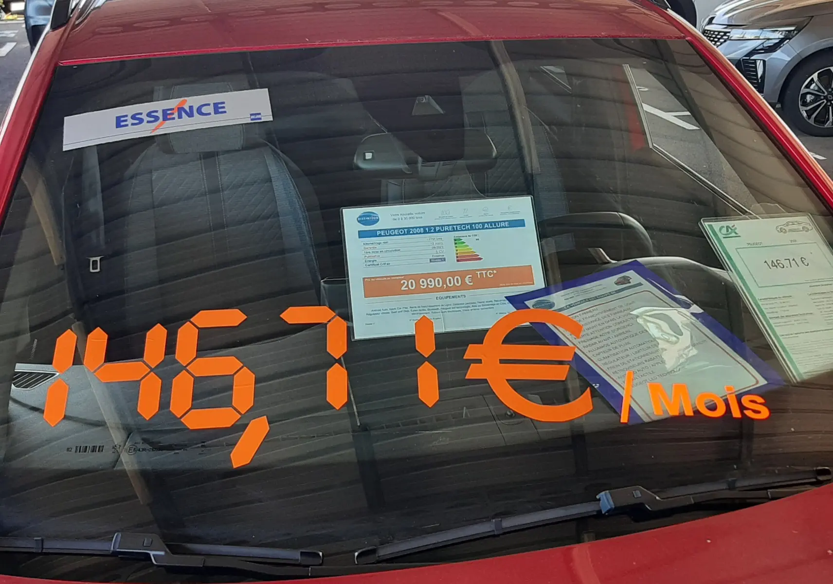 Vue avant rapprochée d'un Peugeot 2008 rouge Elixir 2023 avec affichage orange du loyer mensuel sur le pare-brise.