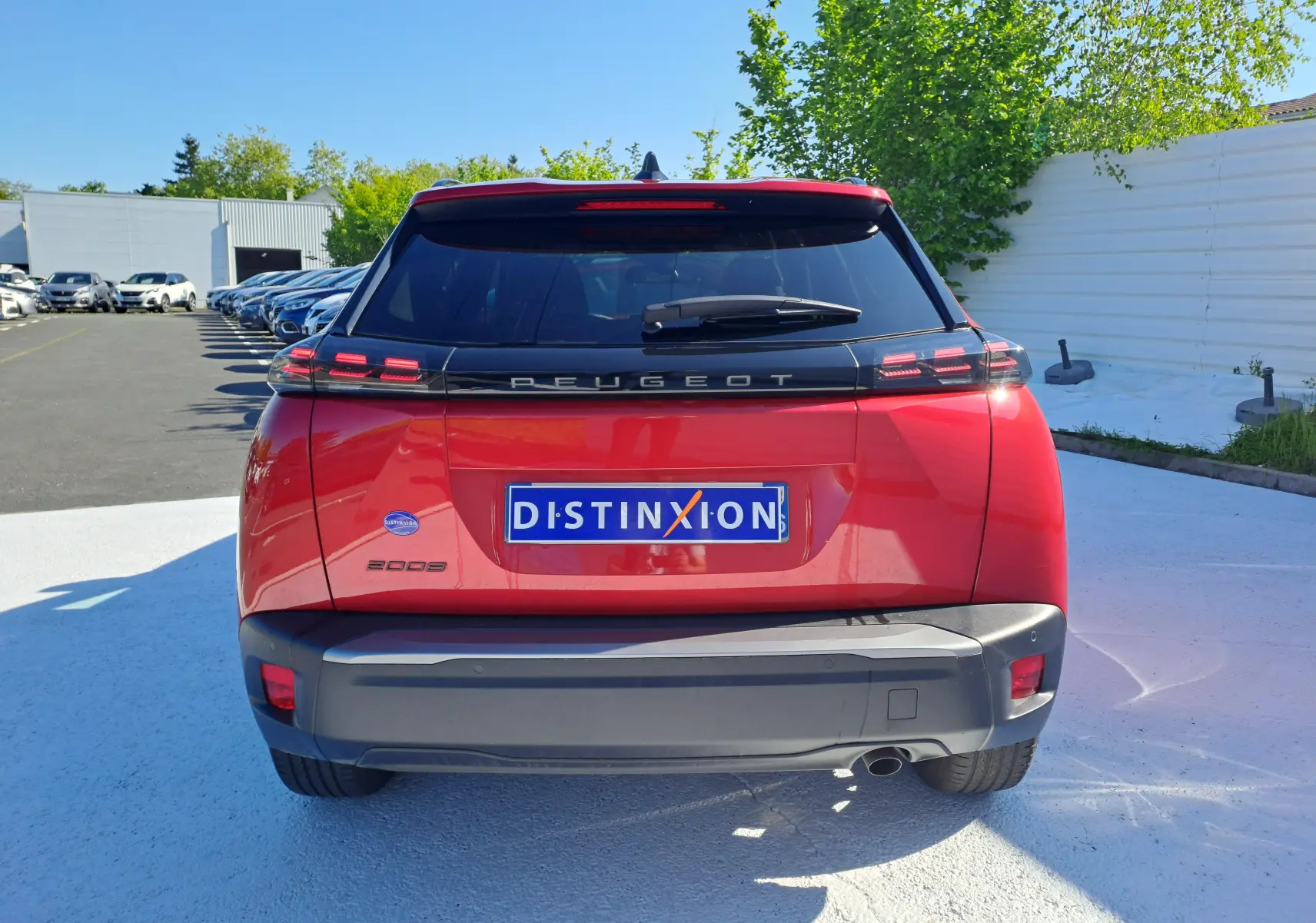 Vue arrière d'un Peugeot 2008 rouge Elixir 2023 avec feux LED et logo distinctif sur parking extérieur.
