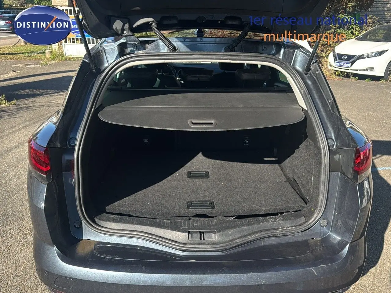 Coffre ouvert vu de l'arrière d'une Renault Mégane Break gris titanium métal, montrant l'espace de chargement vide.