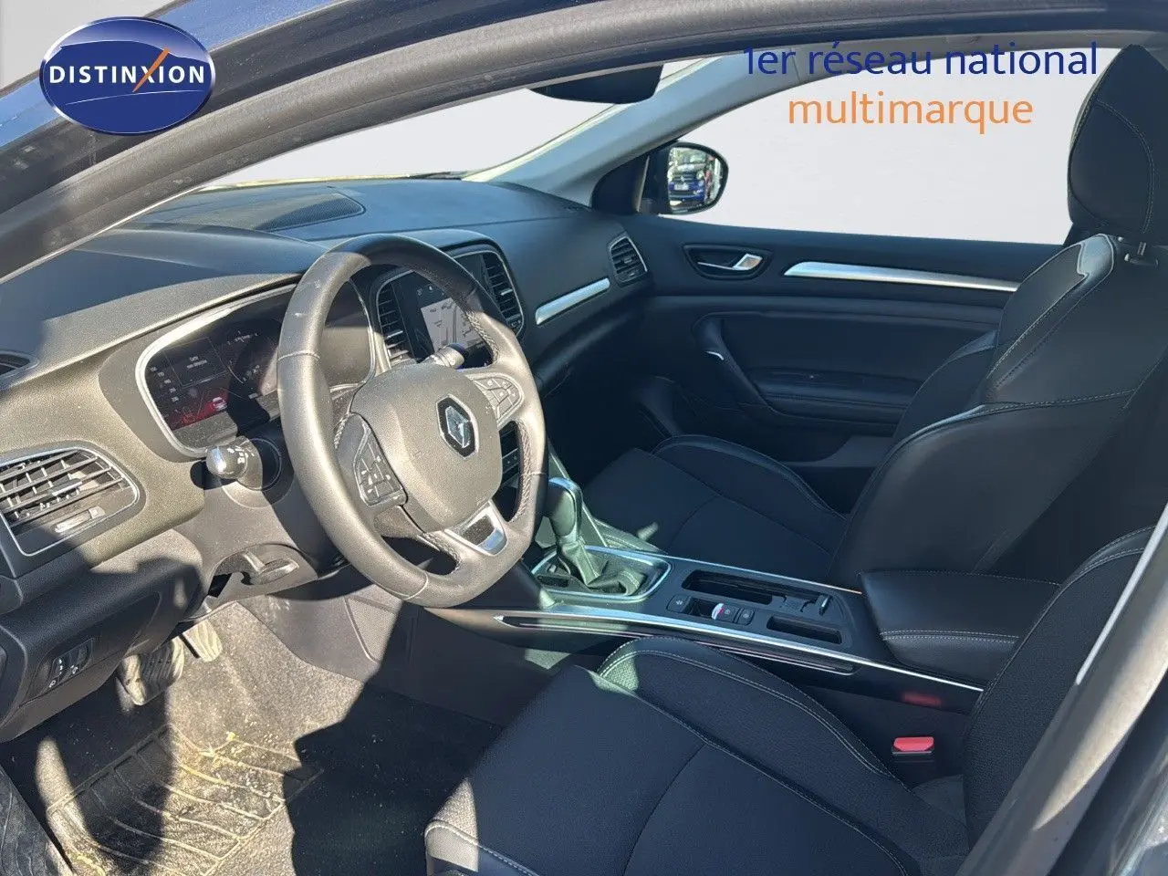 Intérieur avant de la Renault Mégane Break 2024 gris titanium, montrant le tableau de bord et sièges noirs en cuir.