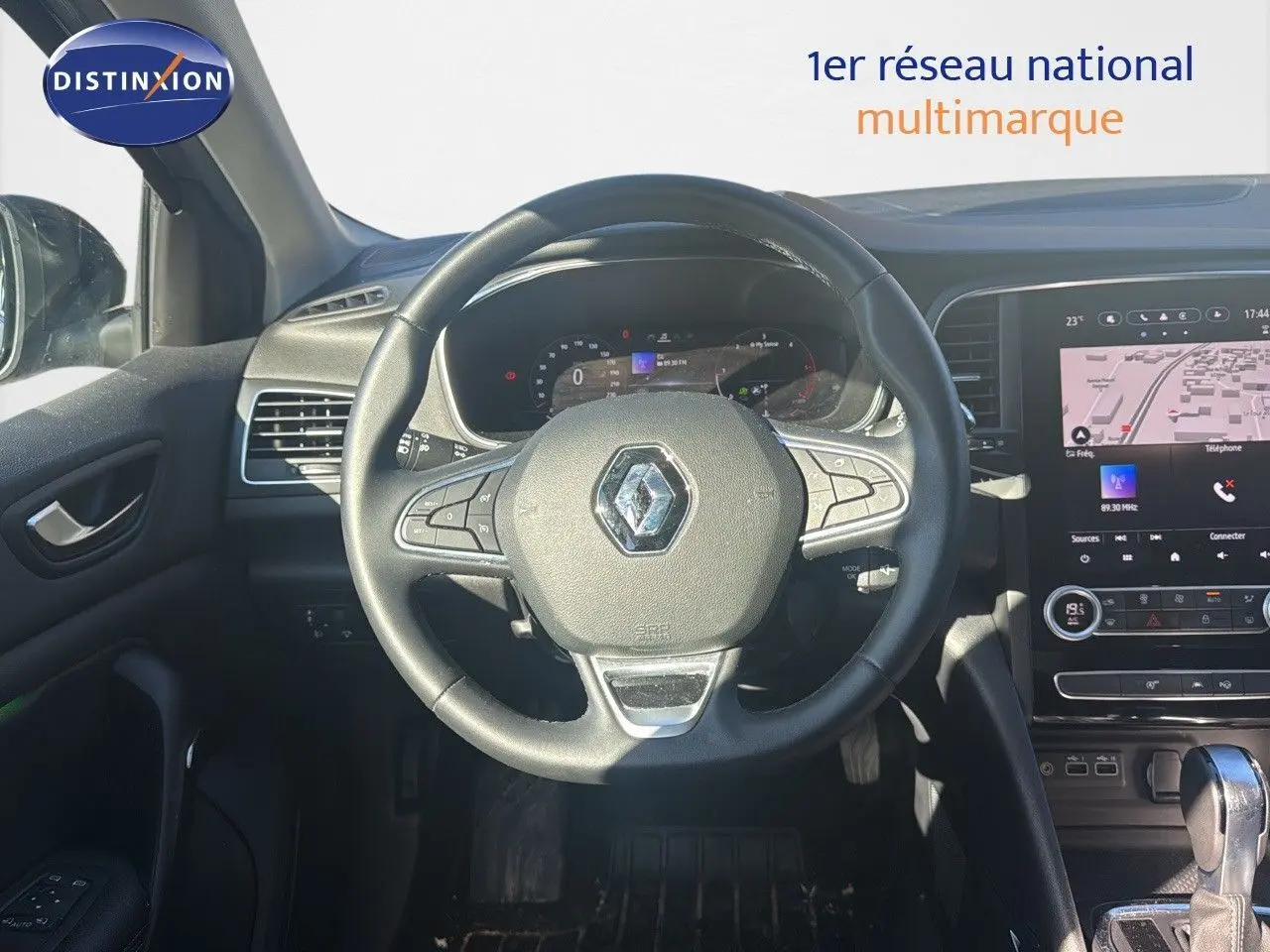 Vue intérieure centrée sur le volant et tableau de bord d'une Renault Mégane Break gris titanium 2024 avec écran tactile et boîte auto.