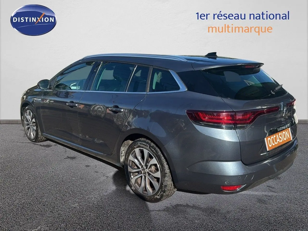 Renault Mégane Break gris titanium métal vue 3/4 arrière droit avec jantes alliage et feux LED allumés.