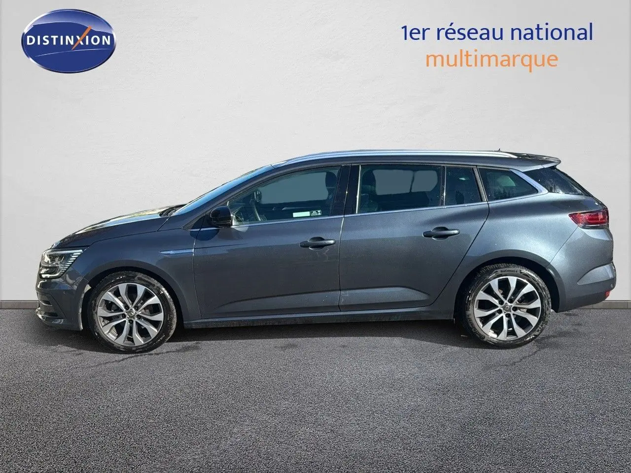 Profil côté gauche d'une Renault Mégane Break gris titanium métal 2024 avec jantes alliage bicolores.