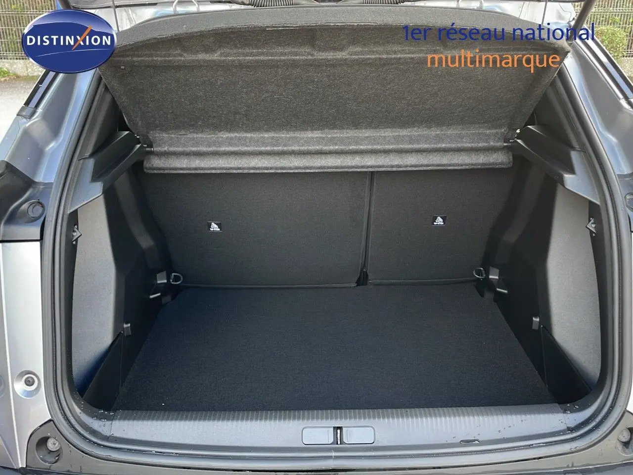 Coffre ouvert vu de l'arrière d'un Peugeot 2008 gris Artense métal, montrant un espace de chargement propre et spacieux.