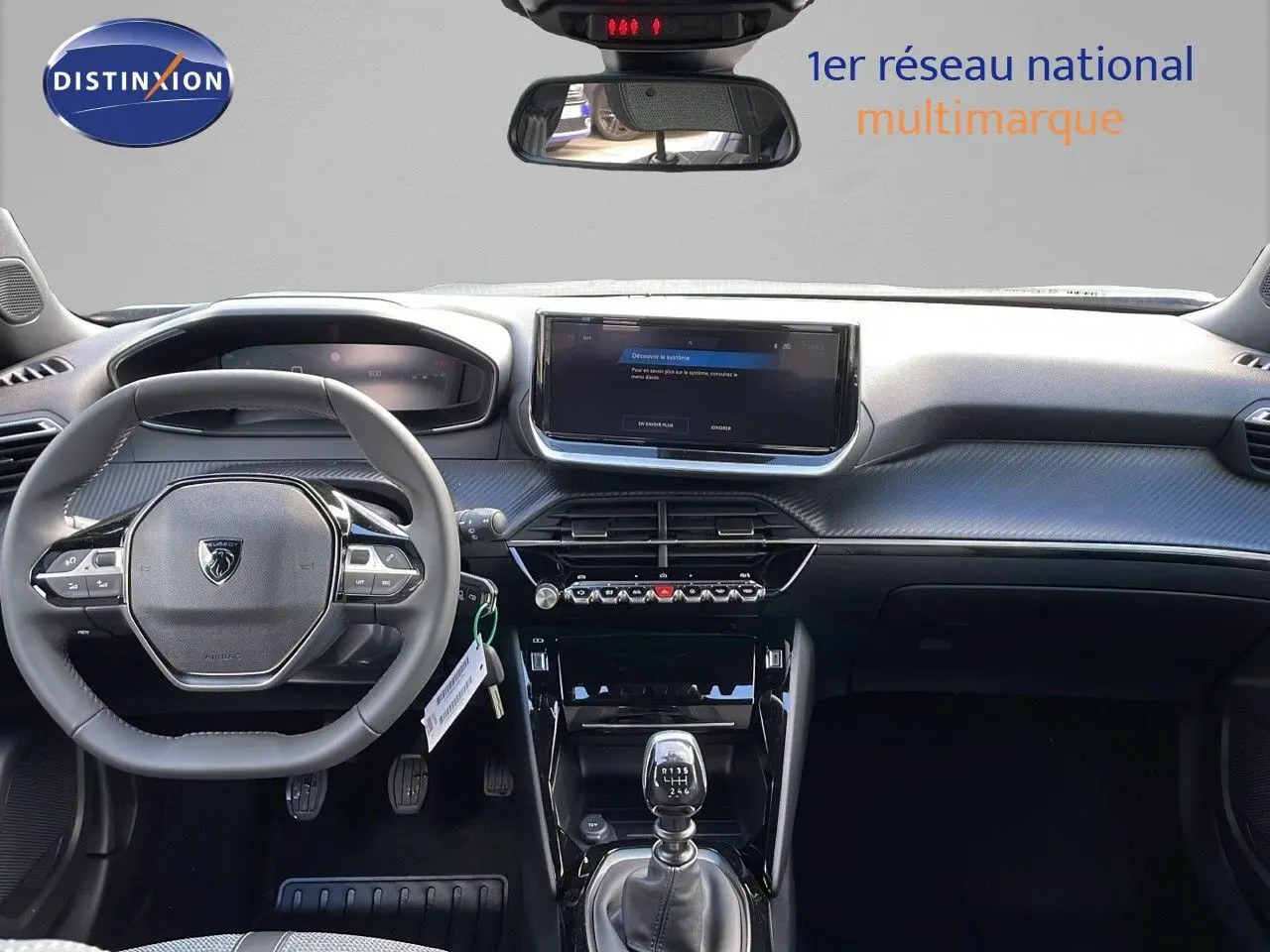 Vue intérieure frontale du tableau de bord et volant gris d'une Peugeot 2008 2025 avec boîte manuelle et écran tactile central.