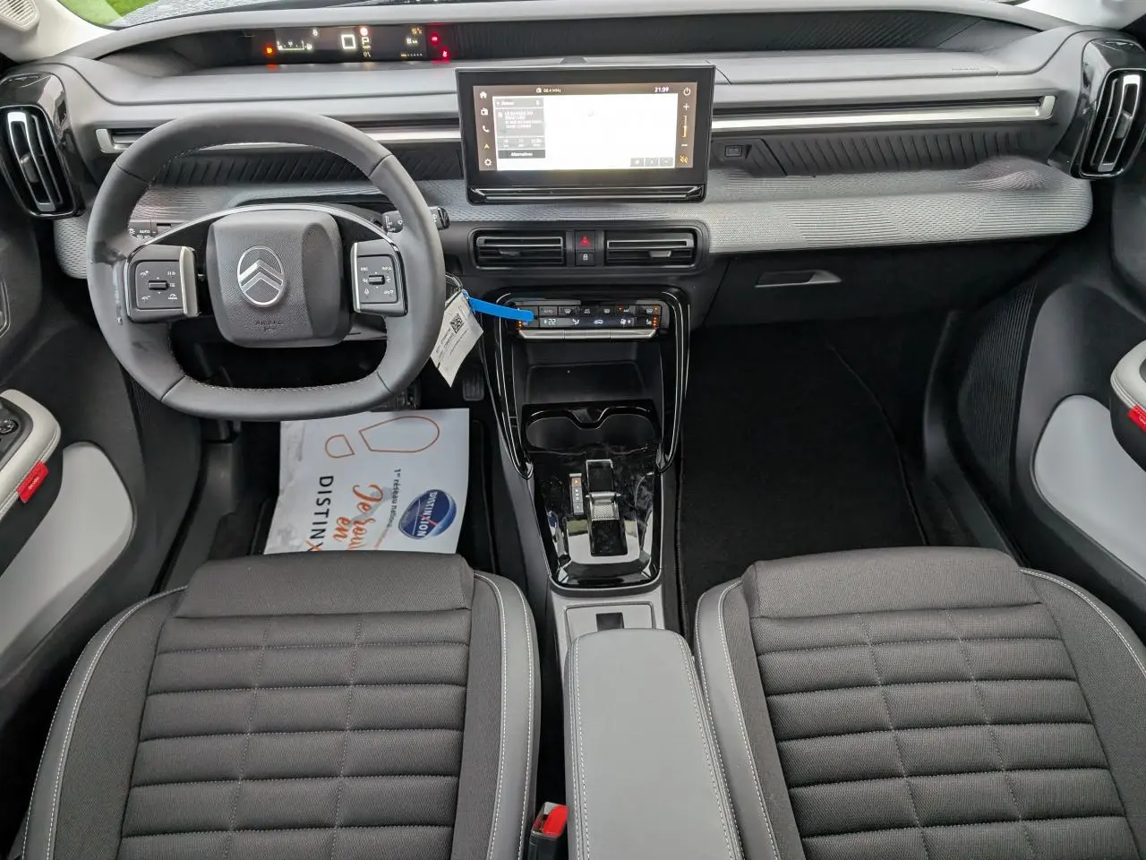 Vue intérieure avant de la Citroën C3 Aircross 2025, planche de bord grise avec écran tactile et volant multifonctions noir.