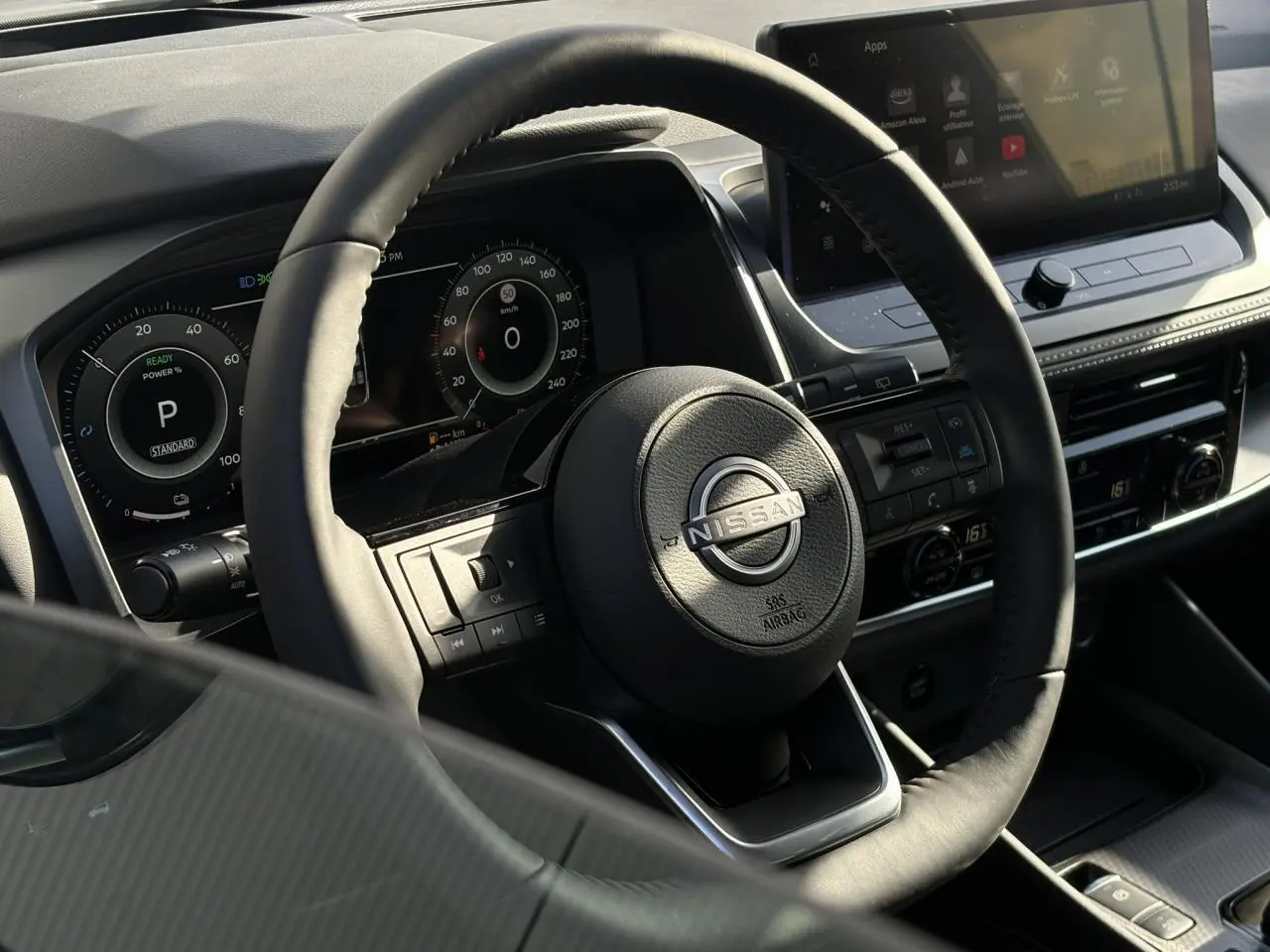 Vue intérieure centrée sur le volant cuir noir et le combiné numérique du Nissan Qashqai 2025, avec écran tactile visible.