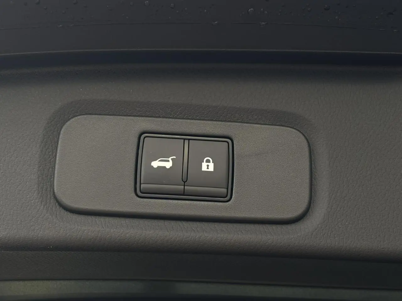 Gros plan sur les boutons d'ouverture électrique et de verrouillage du hayon du Nissan Qashqai noir 2025.