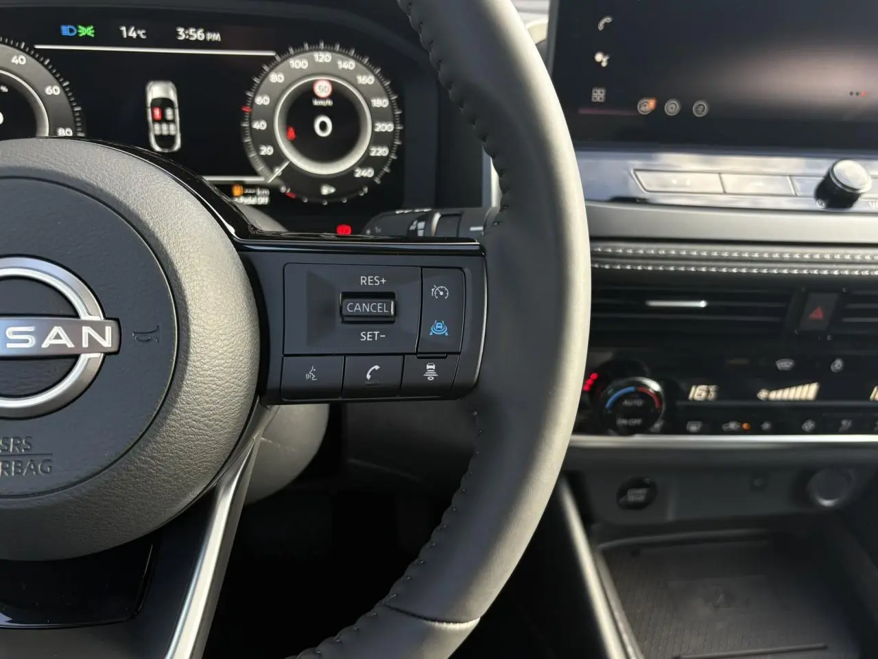 Gros plan sur le volant noir et le tableau de bord numérique du Nissan Qashqai 2025 avec commandes au volant visibles.