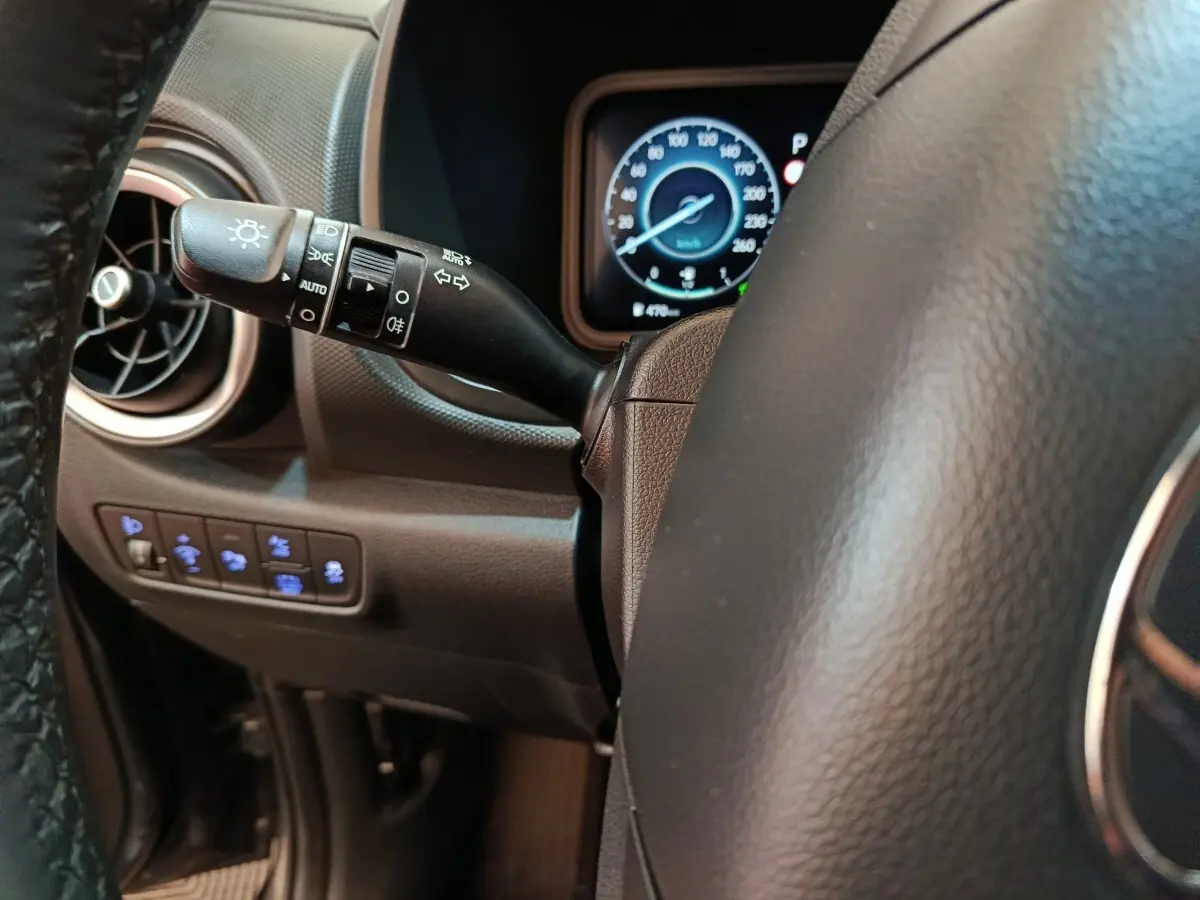 Gros plan sur le volant cuir et la commande des phares à gauche du tableau de bord du Hyundai Kona gris foncé 2023.