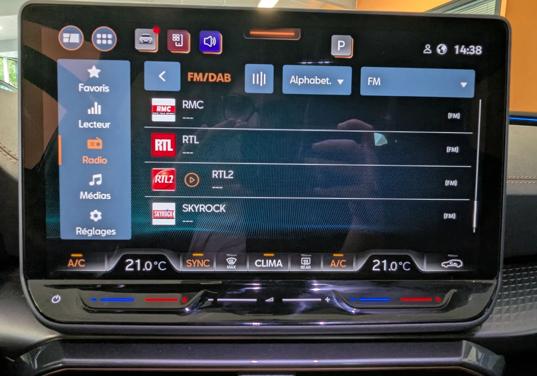 Écran tactile central de 12,9 pouces du CUPRA LEON ST 2025 affichant la liste des radios FM avec commandes climatisation intégrées.