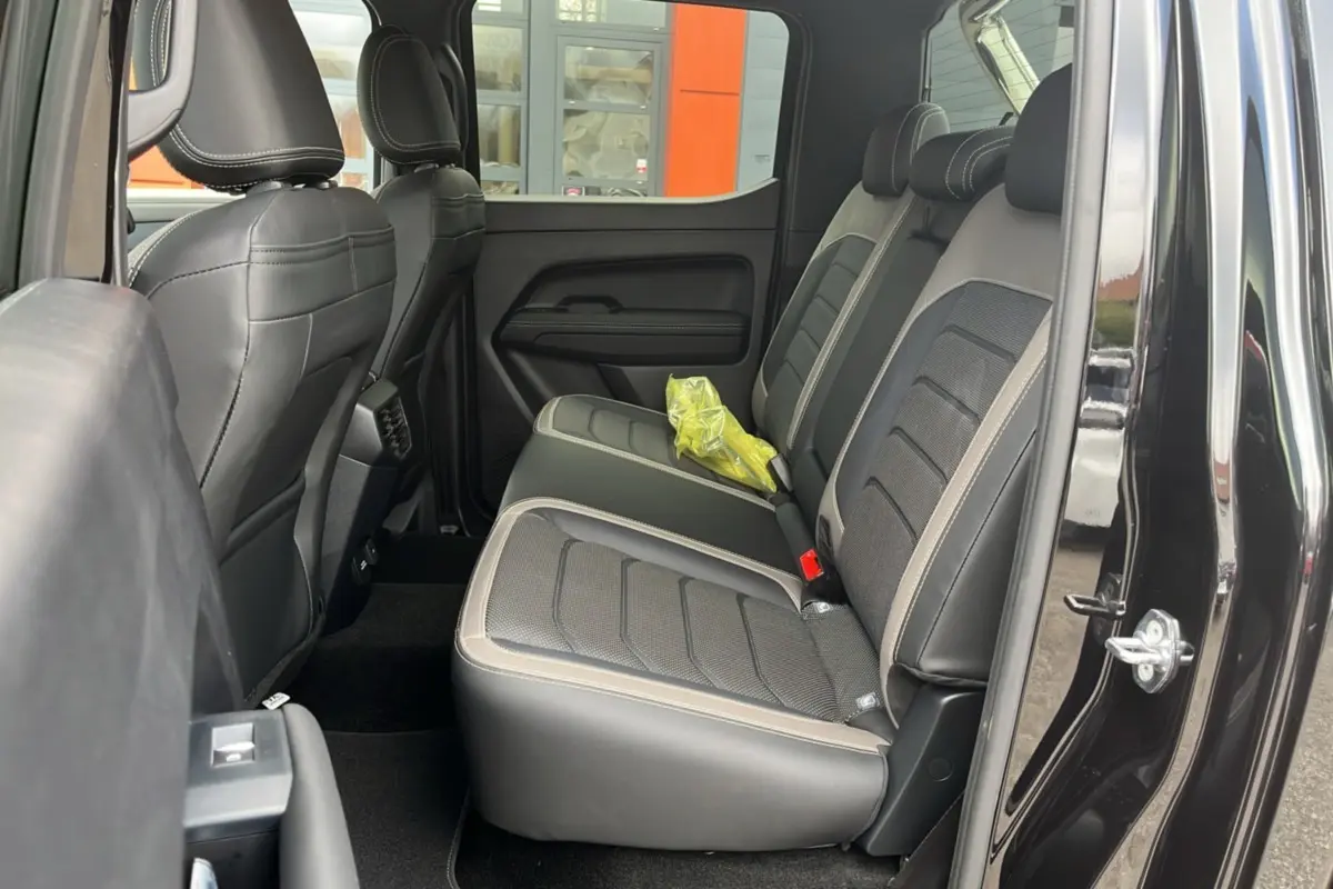 Vue intérieure côté droit sur les sièges arrière en cuir noir et tissu gris du Volkswagen Amarok Simple Cabine noir.