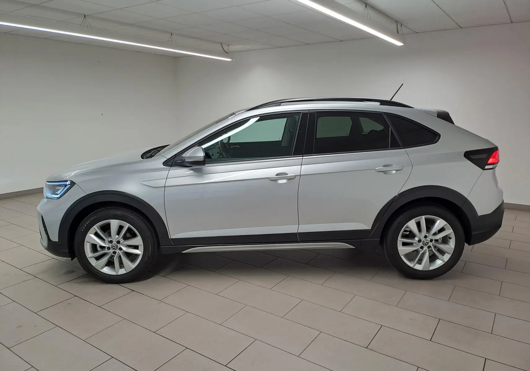 Vue de profil côté gauche d'un Volkswagen Taigo 2025 en peinture métallisée Reflet d'argent avec jantes alliage et toit noir.