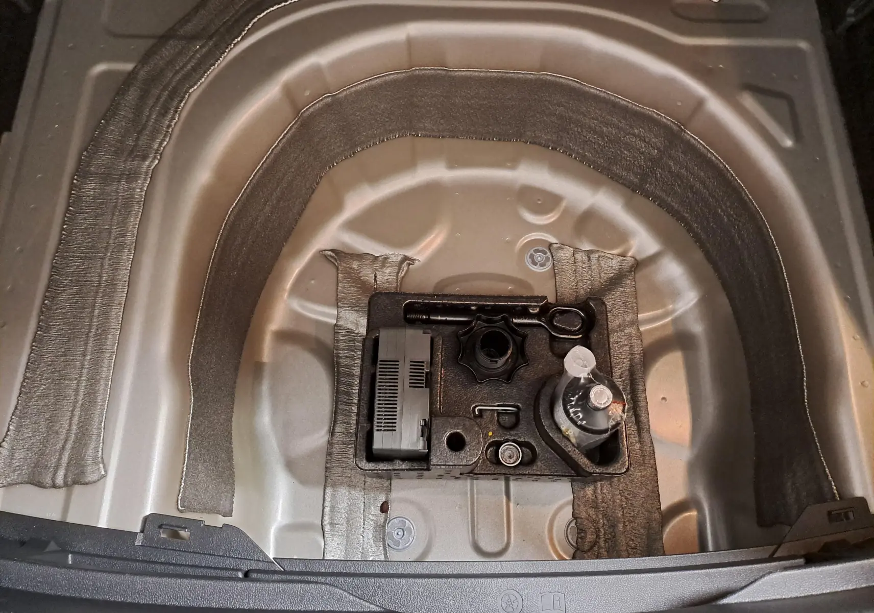 Vue rapprochée du coffre du Volkswagen Taigo 2025, montrant le rangement sous plancher en métal argenté.