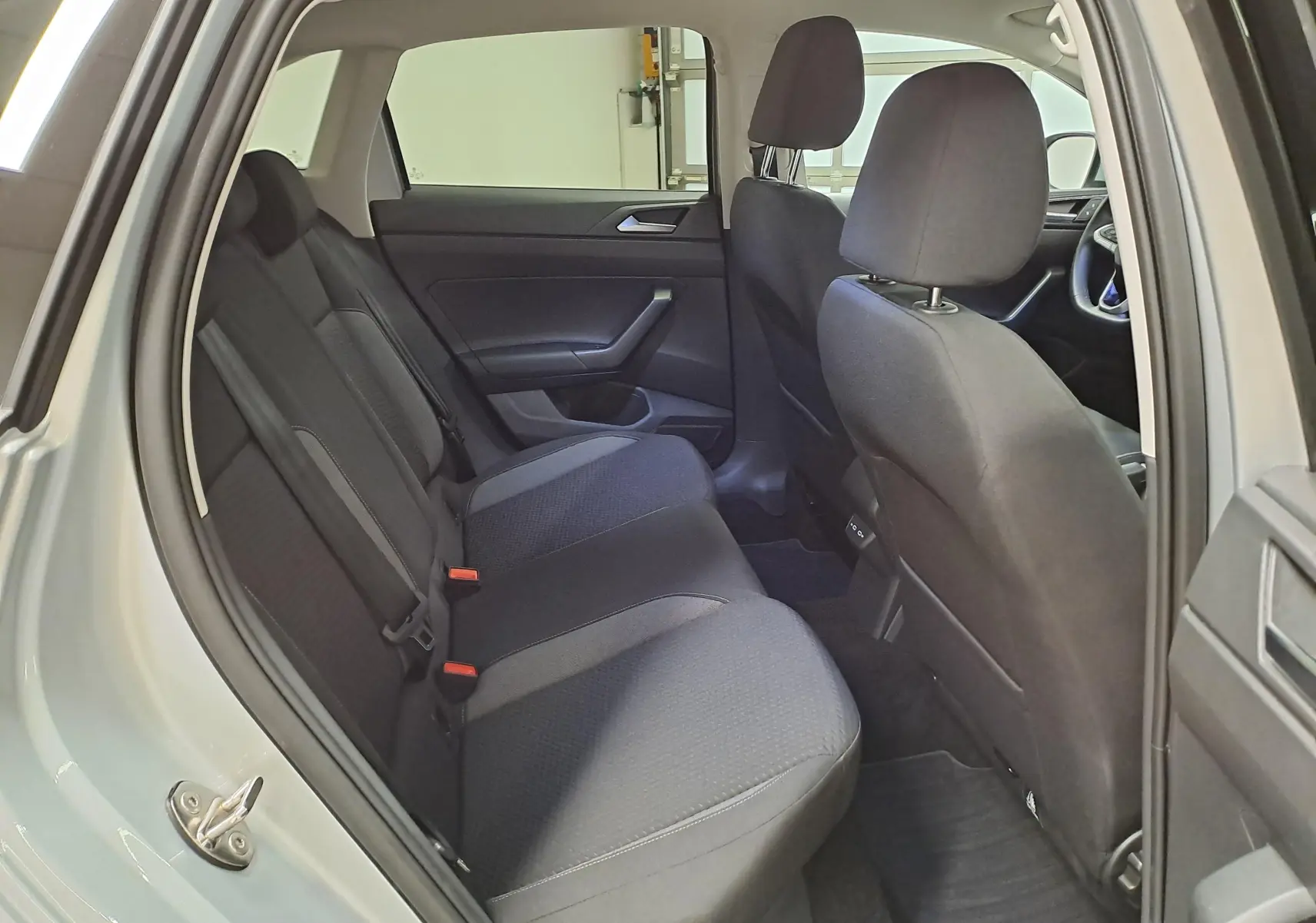 Vue intérieure côté gauche du Volkswagen Taigo 2025, montrant les sièges arrière en tissu noir et la porte ouverte couleur Reflet d'argent.