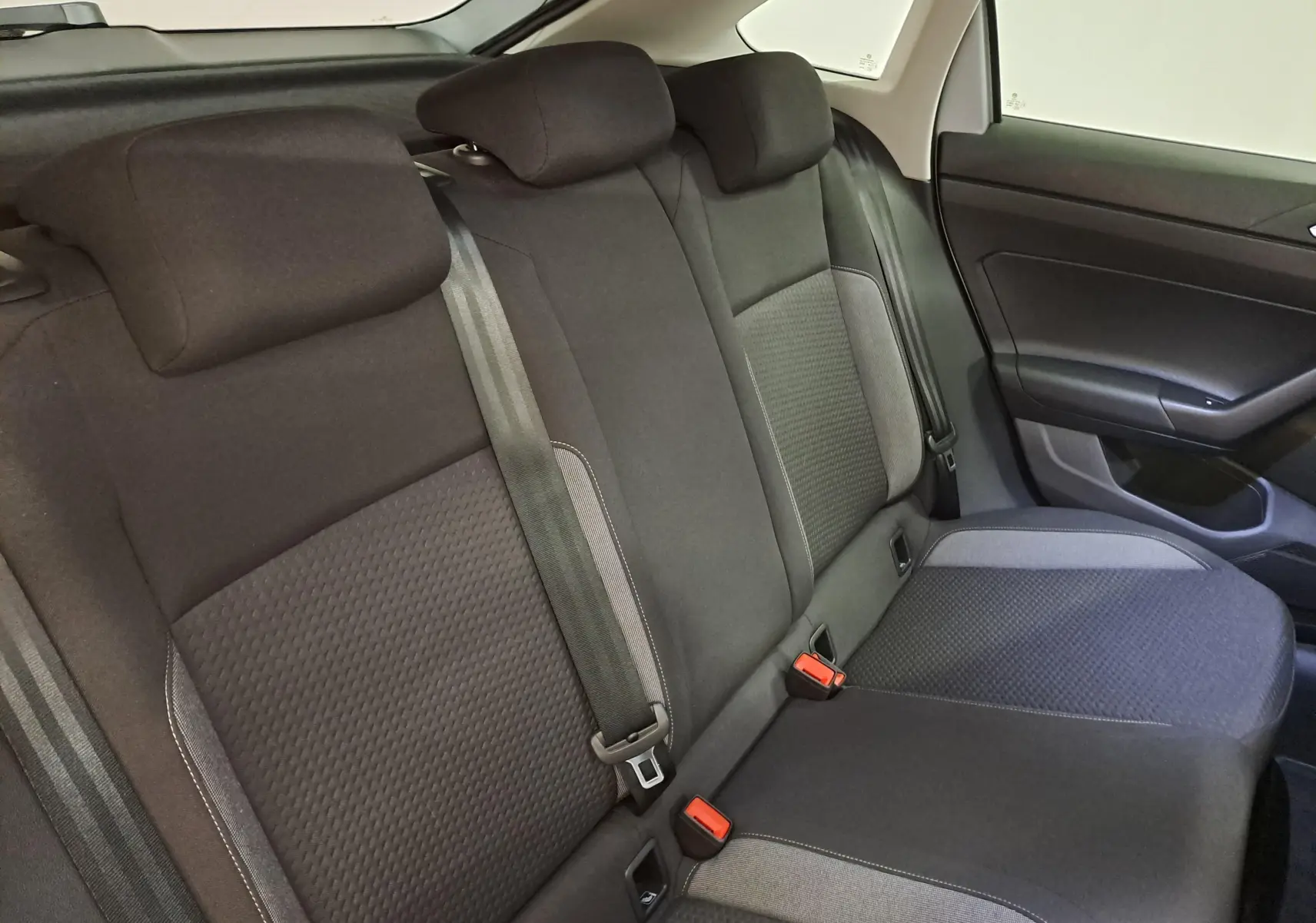 Vue intérieure du siège arrière droit du Volkswagen Taigo 2025, tissu noir avec détails gris et ceintures visibles.